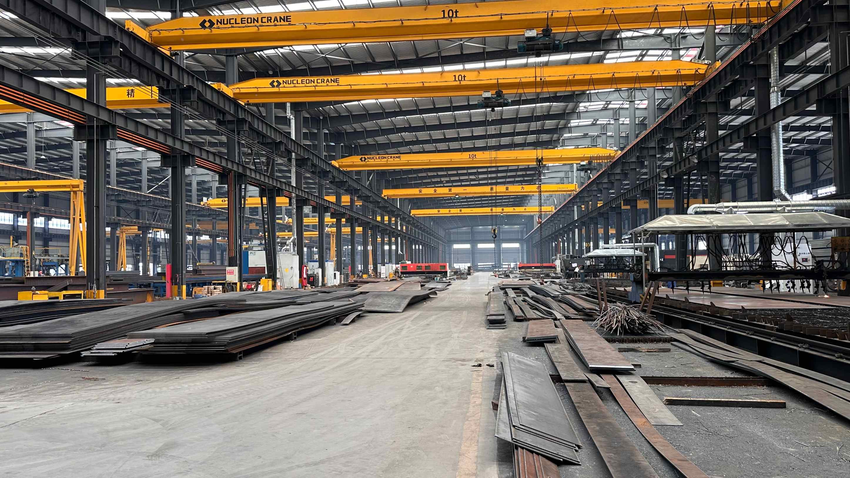 Heavy structural steel fabrication plant in China showing automated welding gantries and overhead cranes handling structural beams for export