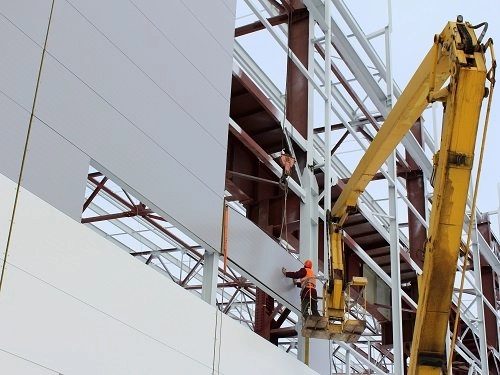Exterior view of insulated PIR sandwich wall panels and standing seam roof installation on steel warehouse